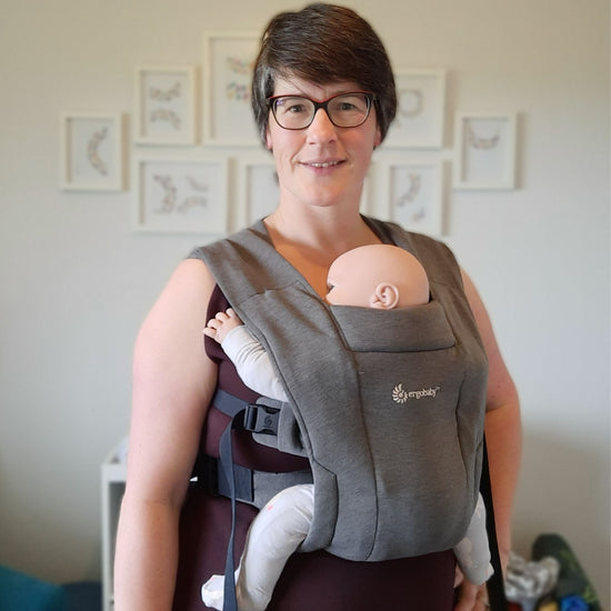 Auckland based babywearing educator wearing a doll in a grey Ergobaby Embrace carrier