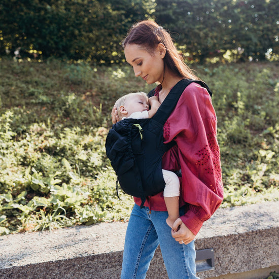 Woman wearing a sleeping infant in a black Boba Air carrier