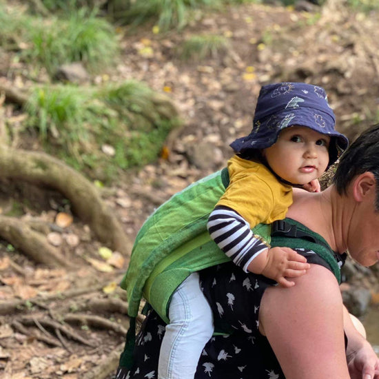Woman crouched wearing a toddler in a green soul onbuhimo 