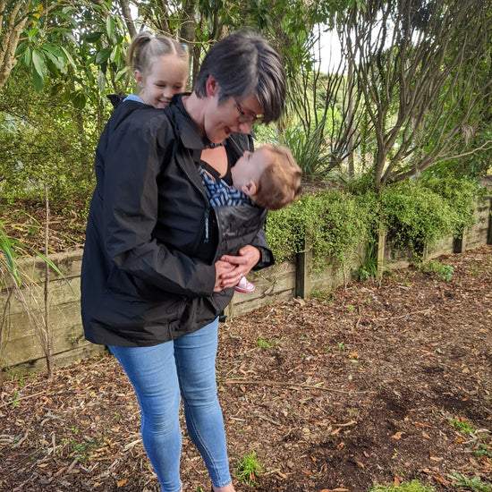 Numbat Go babywearing jacket in Black being worn over a tandem carry