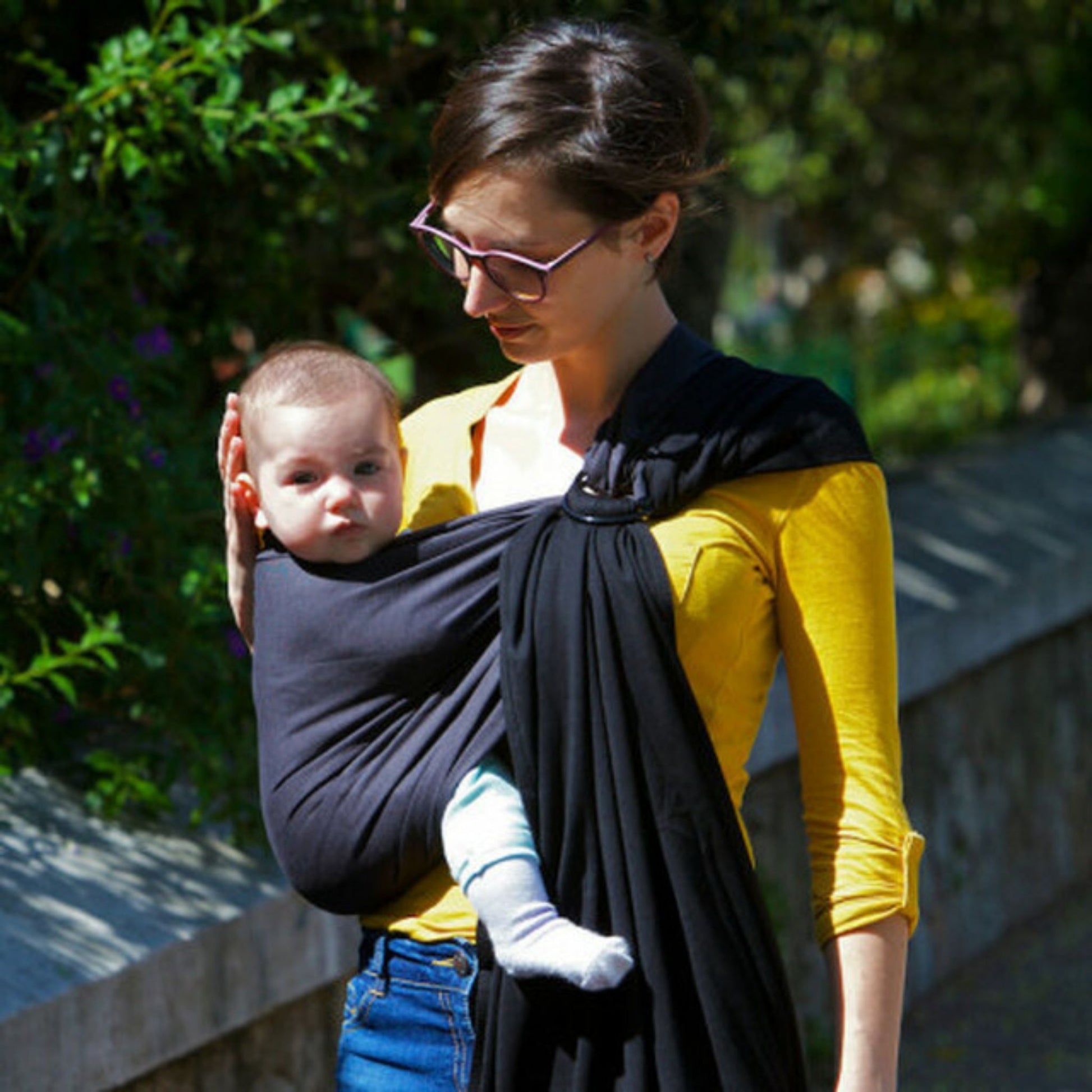 Woman looking at child being carried in a love radius wrap without a knot