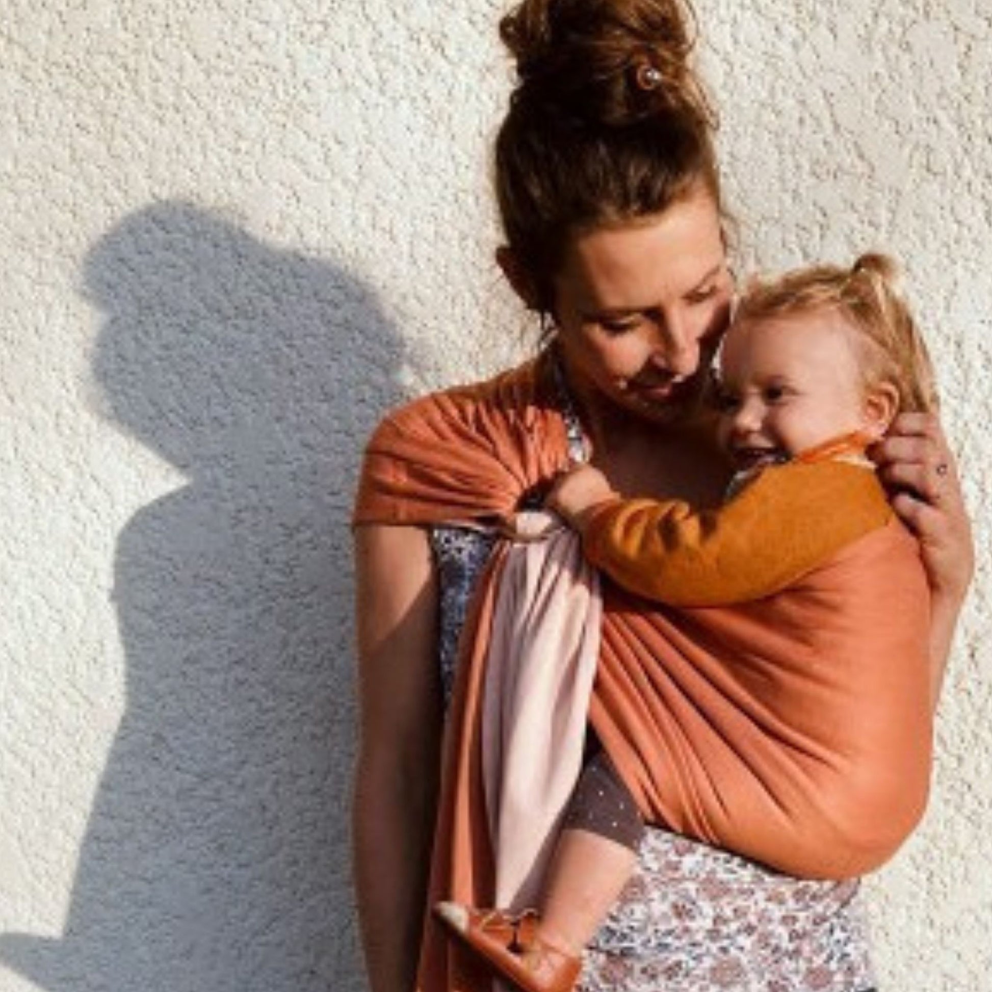 infant being carried in a nude and caramel coloured love radius little wrap without a knot ring sling